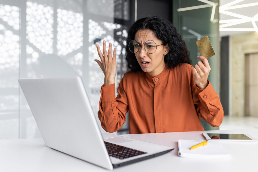 Dissatisfied and angry businesswoman inside the office, hispanic woman at workplace cheated by online fraudsters, female employee trying to transfer money from bank credit card, received error because of not having seo-optimized websites for service-based businesses