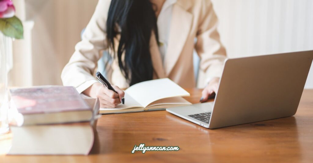 Girl using her pen and writing on her notebook, and using her laptop.